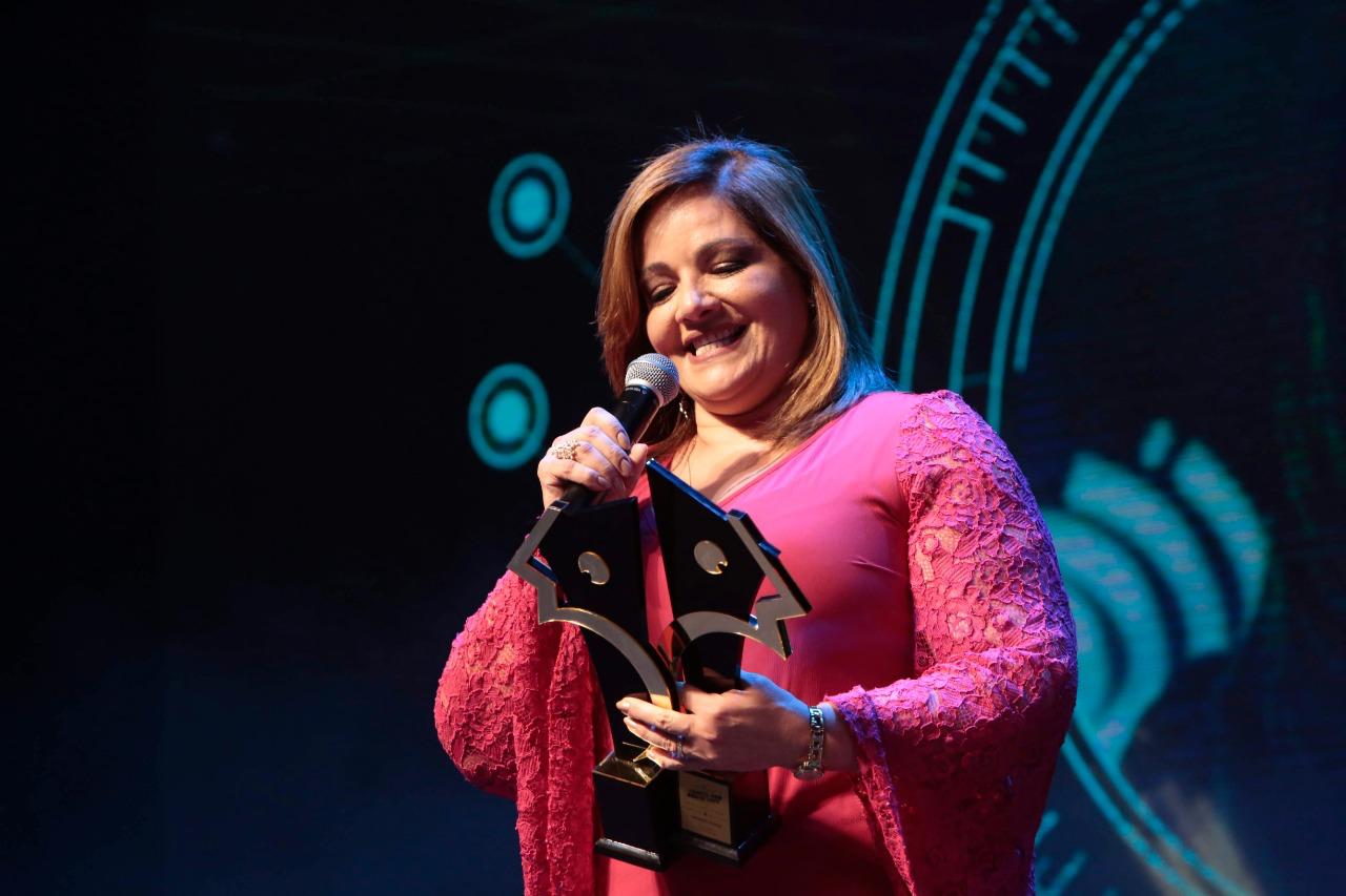 Denise recebendo premiação no palco